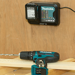 Een Makita boor die zijn zij ligt en een opgehangen DC10SA oplader