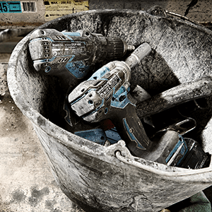 Meerdere Makita machines in een zwarte emmer, met grijs gruis of cement